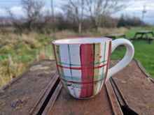 Load image into Gallery viewer, a mug in the foreground with trees and grass in the background