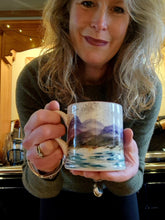 Load image into Gallery viewer, Woman holding a mug with a scenic design in a kitchen setting
