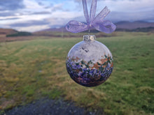 Load image into Gallery viewer, A round decoration bauble with a floral pattern, featuring purple and other colors, hanging against a landscape backdrop.
