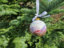 Load image into Gallery viewer, A hand-painted Christmas ornament with a abstract design, featuring a range of colors from purple to green, hanging on a tree.
