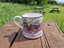Load image into Gallery viewer, A mug with a purple and pink spongeware pattern on it depicting the heather hills of Islay
