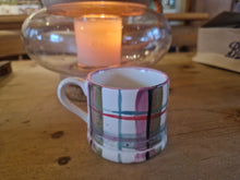 Load image into Gallery viewer, Plaid mug on a wooden table with a warm glow from a lantern in the background
