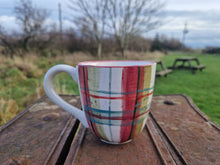 Load image into Gallery viewer, A mug on a bench with trees, grass and picnic benches in the background
